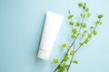 Mockup white Cream bottle tube and birch branches with young small leaves on blue background. Cosmetic product blank plastic Royalty Free Stock Photo