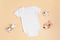 Mockup of white infant bodysuit made of organic cotton with eco friendly baby accessories