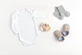 Mockup of white infant bodysuit made of organic cotton with eco friendly baby accessories