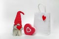 Mockup of a white package with a gnome and a gift box on a light background. Idea valentine's day
