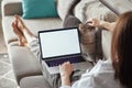Mockup white screen laptop woman using computer and pet cat lying on sofa at home, back view, focus on screen Royalty Free Stock Photo