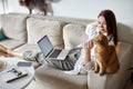 Mockup white screen laptop woman using computer and two pet cat lying on sofa at home Royalty Free Stock Photo