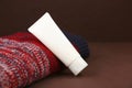 Mockup of white squeeze bottle plastic cosmetic tube for branding and Christmas or autumn red knitted sweater on brown background Royalty Free Stock Photo