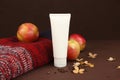Mockup of white squeeze bottle plastic cosmetic tube for branding, red apples, Christmas or autumn red knitted sweater, dry