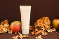 Mockup white squeeze cosmetic tube, cinnamon, autumn apples and dry hydrangea flowers on dark brown background, front view, blank Royalty Free Stock Photo