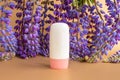 Mockup white tube bottle with pink screw cap for skin care cosmetic summer sunscreen and blue purple lupine flowers on brown