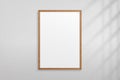 Mockup wood frame photo on wall. Mock up wooden picture framed. Vertical boarder with shadow. Empty photoframe a4 isolated on back