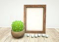 Mockup of wooden frame, pearls, green succulent plant in ceramic on wooden table Royalty Free Stock Photo