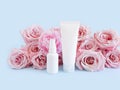 Mockups of two unbranded white bottle for branding and label and light pink roses on a pastel blue background. Royalty Free Stock Photo