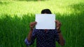 Modal advertisement. Indian Model boy showing a blank white paper in front of Green field for a advertisement company Royalty Free Stock Photo