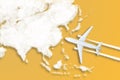 Model airplane design miniature yellow background fluffy clouds in the shape of continent Asia. The idea of tickets for the trip,