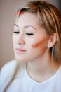 Model while applying makeup, contouring cheekbones.