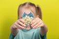 A model of an artificial tooth in the hands of a little girl of seven years old on a yellow background. The concept