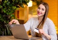 Model with blonde long hair and bright pink lipstick in white sweater sitting on a chair in a cafe with beautiful stylish interior Royalty Free Stock Photo