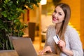 Model with blonde long hair and bright pink lipstick in white sweater sitting on a chair in a cafe with beautiful stylish interior Royalty Free Stock Photo