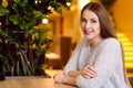 Model with blonde long hair and bright pink lipstick in white sweater sitting on a chair in a cafe with beautiful stylish interior Royalty Free Stock Photo