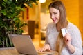 Model with blonde long hair and bright pink lipstick in white sweater sitting on a chair in a cafe with beautiful stylish interior Royalty Free Stock Photo