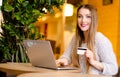 Model with blonde long hair and bright pink lipstick in white sweater sitting on a chair in a cafe with beautiful stylish interior Royalty Free Stock Photo