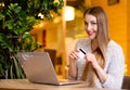 Model with blonde long hair and bright pink lipstick in white sweater sitting on a chair in a cafe with beautiful stylish interior Royalty Free Stock Photo