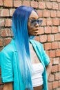 Model with blue hair wearing a white top and a turquoise jacket