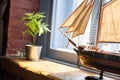 Model of a boat and flower in a pot on a wooden window sill in an old house Royalty Free Stock Photo