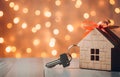 Model of cardboard house with key against bokeh background. house building, loan, real estate or buying a new home Royalty Free Stock Photo