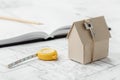 Model cardboard house with key and tape measure on blueprint. Home building, architectural and construction design concept