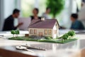 A Model Of A Compact House On A Table Next To The Keys In An Estate Agency