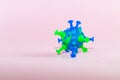 A model of a coronavirus bacterium made of blue green plasticine on a pink paper background. Topic protection, danger from the spr