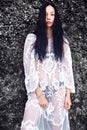 Model with dark long hair in transparent white long blouse dress posing near rocks Royalty Free Stock Photo