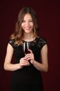 Model in dress holding glass of wine. Close up. Dark red background Royalty Free Stock Photo