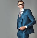 Model dressed in elegant blue suit posing on gray background in studio in glasses Royalty Free Stock Photo