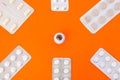 Model of eye surrounded by six blister packs with white pills inside in corners of image on orange background. Photo concept art