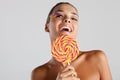 Model with fake feather eyelashes holds a round-shaped rainbow lollipop smiles Royalty Free Stock Photo