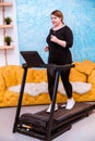 Model - a fat woman, trying to lose weight and at home engaged on a treadmill