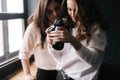 Model and female photographer looking at made photo and smiling in studio.