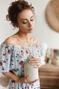 Model girl with curly hair and slim body in light spring dress posing in the home interior. Summer fashion