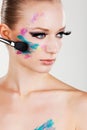 Model girl with fake eyelashes colourful glittery face paint blusher brush Royalty Free Stock Photo