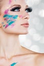 Model girl with fake eyelashes colourful glittery face paint Creative makeup