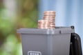 A model of a gray trash can containing recyclable trash in the garbage sorting process opens the lid and comes out with dollar coi
