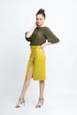 Model in green blouse, yellow suede skirt with yellow belt, isolated on white background.