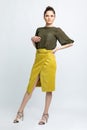 Model in green blouse, yellow suede skirt with yellow belt, white heeled sandals isolated on white background. Royalty Free Stock Photo