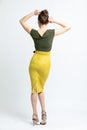 Model in green blouse, yellow suede skirt with yellow belt, white heeled sandals isolated on white background. Royalty Free Stock Photo