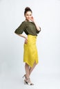 Model in green blouse, yellow suede skirt with yellow belt, white heeled sandals isolated on white background. Royalty Free Stock Photo