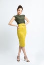 Model in green blouse, yellow suede skirt with yellow belt, white heeled sandals  on white background. Royalty Free Stock Photo