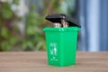 A model of a green trash can with dollar coins coming out of the lid