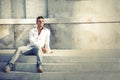 Model handsome man relaxed sitting on the steps of white marble. Royalty Free Stock Photo