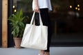 Model hold blank white fabric mockup bag for save environment on street fashion