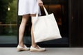 Model hold blank white fabric mockup bag for save environment on street fashion