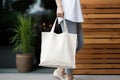 Model hold blank white fabric mockup bag for save environment on street fashion